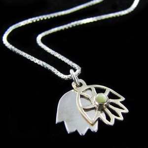 May include: A silver chain necklace with a pendant featuring a silver and gold lotus flower design with a green gemstone in the centre.