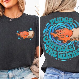 The image is a collage of two photos showing the back of a woman wearing a black t-shirt with a graphic design featuring an orange fish and the text "Pudge Controls the Weather".