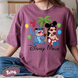 A person wearing a purple t-shirt with a Disney-themed graphic of Lilo and Stitch, along with various Disney characters and balloons.
