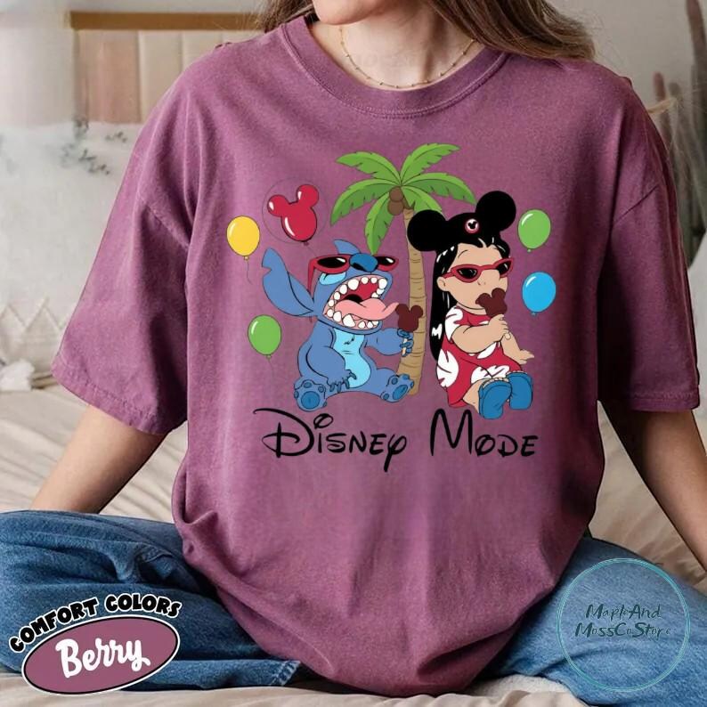 A person wearing a purple t-shirt with a Disney-themed graphic of Lilo and Stitch, along with various Disney characters and balloons.