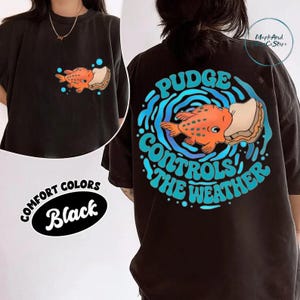 The image is a collage of two photos. The first photo shows a person wearing a black t-shirt with a graphic of a fish and the text "Pudge Control the Weather" printed on it. The second photo shows the back of the same t-shirt, featuring the same graphic and text.