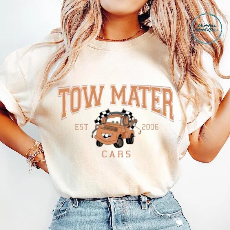 A woman wearing a white t-shirt with a graphic of a tow truck and the text "TOW MATE" printed on it.