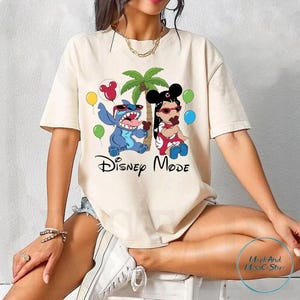 A woman wearing a white t-shirt with a Disney-themed graphic of characters Stitch and Minnie Mouse, along with the text "Disney Mode".