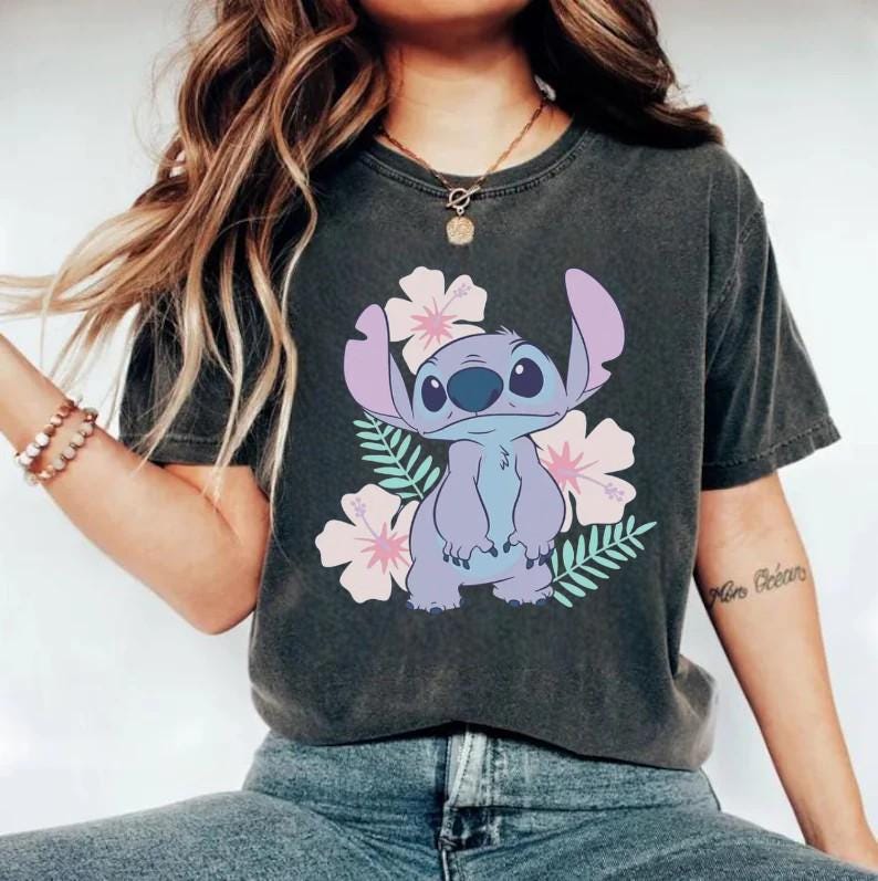 A woman wearing a black t-shirt with a graphic of a cartoon character and flowers printed on it.