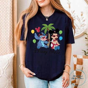 A woman wearing a black t-shirt with a graphic design featuring characters from the Disney movie "Stitch".
