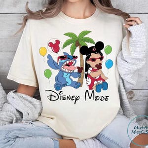 A woman wearing a white t-shirt with a Disney-themed graphic design featuring characters from the Disney movie Lilo and Stitch.