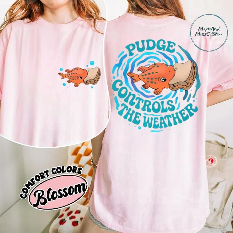 The image is a collage of two photos. In the first photo, a person is wearing a pink t-shirt with a cartoon fish and the text "Pudge Control the Weather" printed on it. In the second photo, the person is wearing a pink t-shirt with the text "Short Colors Blossom" printed on it.