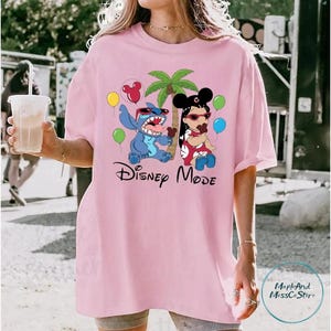 A woman wearing a pink t-shirt with a Disney-themed graphic of Stitch and Minnie Mouse.