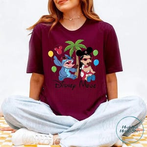 A woman wearing a maroon t-shirt with a Disney-themed graphic of characters from the movie Lilo & Stitch.