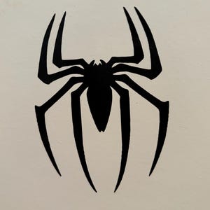 May include: A black spider emblem with eight legs, a segmented body, and a pointed head. The spider is centered on a white background. The spider's legs are long and curved, with pointed tips.