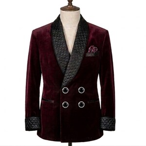 May include: A burgundy velvet double-breasted blazer with a black quilted satin shawl collar, pocket square, and cuffs. The blazer features four silver buttons and a notched lapel. A stylish formal jacket.