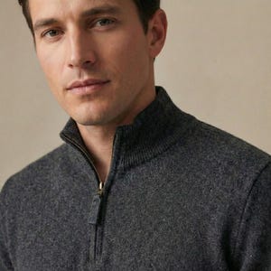 Peut inclure: Un pull gris anthracite à fermeture éclair quart de tour avec un col montant côtelé et une fermeture métallique. Le vêtement est fabriqué dans un tissu en maille texturée à l'aspect chiné, offrant une teinte gris foncé uniforme sur l'ensemble.