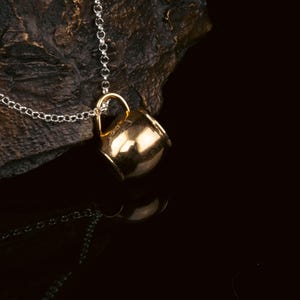 May include: A gold-tone necklace with a small, detailed, gold-tone mug pendant.