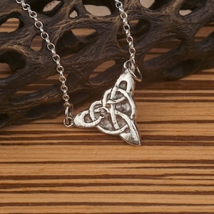 May include: A silver Celtic knot pendant necklace with a triangular shape. The pendant is detailed with intricate knotwork and hangs from a silver chain.