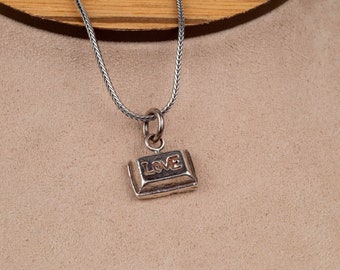 May include: Silver necklace with a rectangular pendant that says "LOVE" in a stylized font.