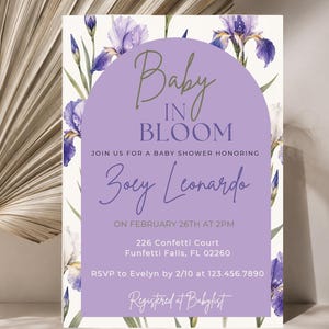 May include: A rectangular baby shower invitation card featuring watercolor purple iris flowers on the edges and a central lavender arch. The text reads: Baby IN BLOOM, JOIN US FOR A BABY SHOWER HONORING Zoey Leonardo, ON FEBRUARY 26TH AT 2PM, 226 Confetti Court, Funfetti Falls, FL 02260, RSVP to Evelyn by 2/10 at 123.456.7890, Registered at Babylist.