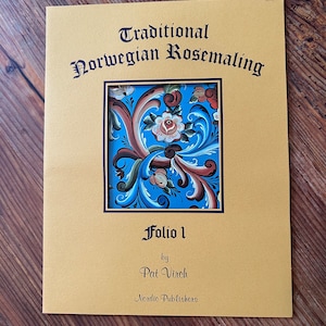 以下が含まれることがあります： 黄色の本の表紙に、黒い文字で「Traditional Norwegian Rosemaling」というタイトルが書かれています。表紙には、青い枠で囲まれた、青と白のローズマリングのデザインが描かれており、赤いアクセントが付けられています。この本は「Folio 1」というタイトルで、Pat Virch、Nordic Publishersによって出版されています。