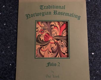 May include: A green book cover with the title "Traditional Norwegian Rosemaling Folio 2" by Pat Virch and Nordic Publishers. The cover features a colorful floral design in red, orange, yellow, green, and black.