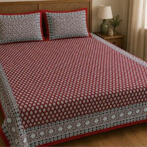 May include: A bed sheet set featuring a deep red base with a repeating white and dark blue teardrop pattern. The set includes two matching rectangular pillowcases with a central geometric circular design and a wide decorative border in light blue.