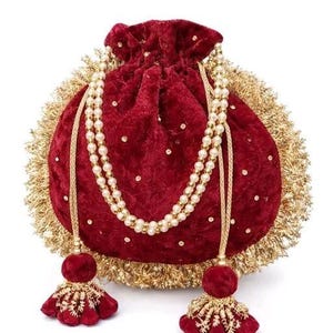 May include: A deep red velvet drawstring pouch featuring a gold metallic fringe border, scattered gold sequins, and a double-strand pearl handle. The bag includes two matching red velvet tassels with gold embroidery at the base of the drawstrings.