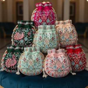 Può includere: Una collezione di borse ricamate con coulisse in vari colori, tra cui rosa, verde e rosso. Le borse presentano intricati motivi floreali e geometrici con dettagli di perline. Alcune borse hanno un design a pavone.