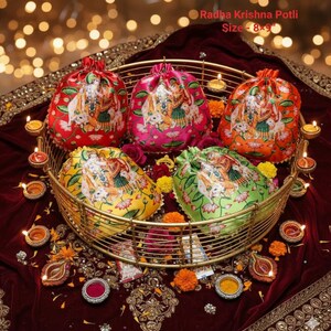 May include: Five colorful drawstring bags, each with a printed image of Radha Krishna, are displayed in a gold-colored basket. The bags are red, pink, orange, yellow, and green. The text "Radha Krishna Potli Size - 8x9" is visible.