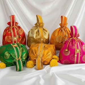 Puede incluir: Colección de seis coloridas bolsas con cordón en rojo, dorado, naranja, verde, amarillo y rosa. Cada bolsa presenta un patrón floral dorado, ribete dorado y un asa a juego. Dispuestas sobre una superficie de satén blanco.