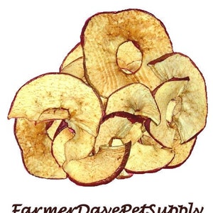May include: A pile of dried apple slices, some are whole and some are cut into pieces. The slices are a light brown color with some red showing through.