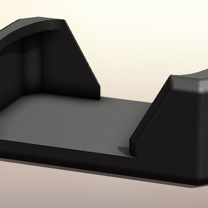 May include: A black, geometric object with a rectangular base and curved, angled sides. The interior is a flat, gray surface. The object appears to be a holder or stand, possibly for a phone or small device. The design is minimalist and modern.