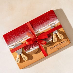 Könnte beinhalten: Ein Holz-Käsebrett mit einem rot-weißen Harzdesign, kombiniert mit zwei passenden Untersetzern und Käsemessern. Das Brett ist mit einem roten Band gebunden und trägt die Namen "Patrick & Kelly" und das Jahr "EST:2025".