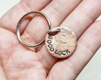 Può includere: Un portachiavi in ​​rame con le parole "GOOD LUCK" incise su di esso. La moneta è datata 2016 e ha un portachiavi d'argento.