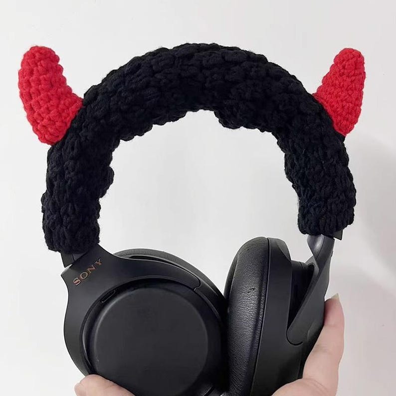 K&ouml;nnte beinhalten: Schwarzer Kopfh&ouml;rer mit einem geh&auml;kelten Teufelshorn-Stirnband. Das Stirnband ist schwarz mit zwei roten H&ouml;rnern. Der Kopfh&ouml;rer ist schwarz und tr&auml;gt den Markennamen "SONY". Das Stirnband ist so konzipiert, dass es &uuml;ber den Kopfh&ouml;rer passt.
