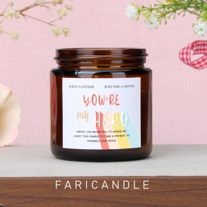 Può includere: Una candela in barattolo di vetro marrone con un'etichetta bianca che recita "YOU'RE my HERO". La candela ha un profumo di lavanda e un tempo di combustione di 16 ore. Il fondo del barattolo recita "FARICANDLE".