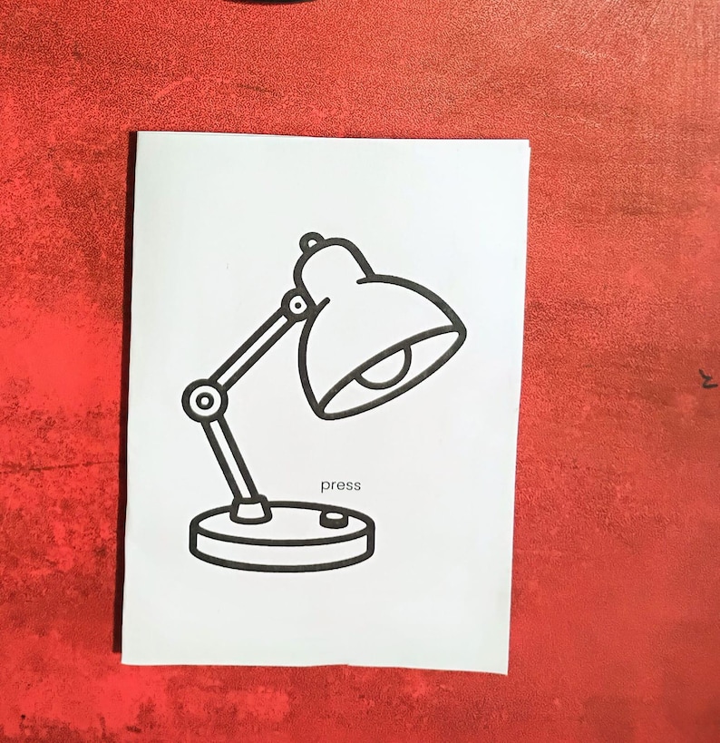 May include: A black and white line drawing of a desk lamp on a white background. The lamp has a rounded shade, an adjustable arm, and a circular base. The word "press" is written below the base.