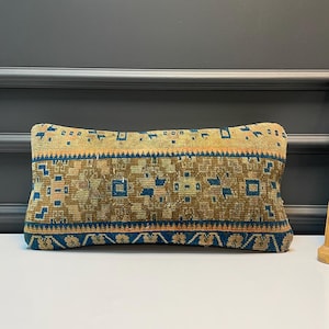 Puede incluir: Cojín decorativo rectangular con un patrón geométrico en tonos marrón, azul y naranja. El cojín presenta un diseño texturizado y tejido, que añade un toque de encanto rústico. Ideal para añadir un toque de color y patrón a cualquier espacio habitable.