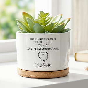 May include: A white ceramic planter with a bamboo base containing a green succulent. The planter features black text that reads: NEVER UNDERESTIMATE THE DIFFERENCE YOU MADE AND THE LIVES YOU TOUCHED, a stethoscope heart icon, and the name Nurse Smith.