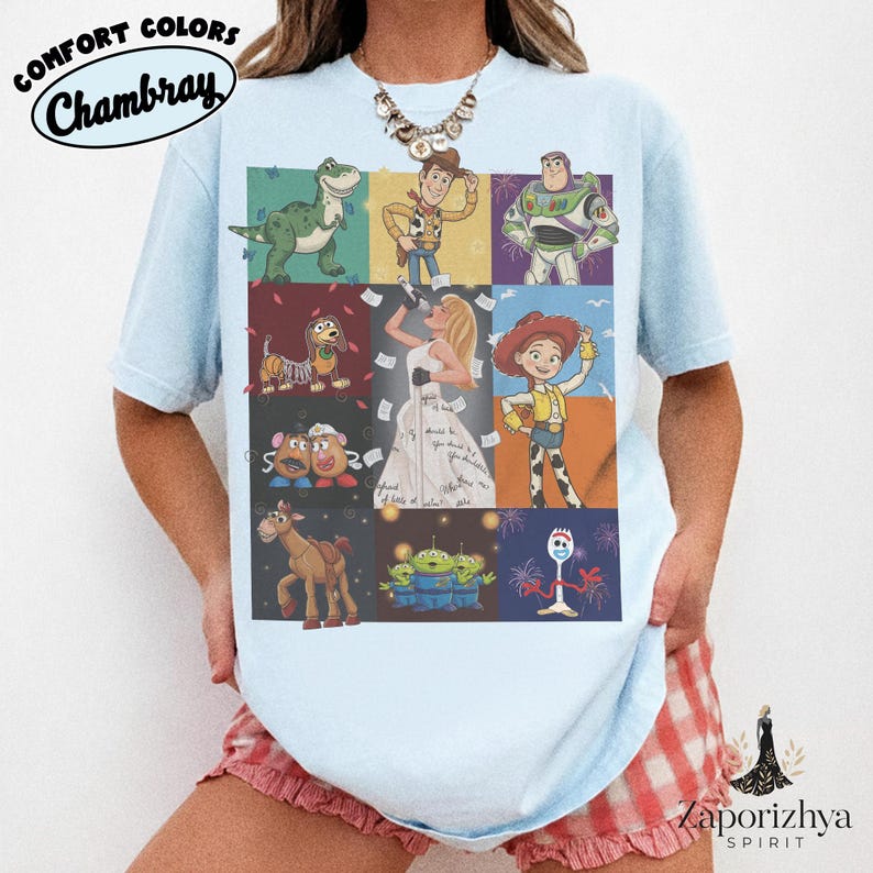 May include: A light blue t-shirt featuring a grid of nine panels displaying various animated characters, including a dinosaur, a cowboy, a space ranger, a dog, a singer in a white dress, a cowgirl, potato figures, a horse, aliens, and a fork character.