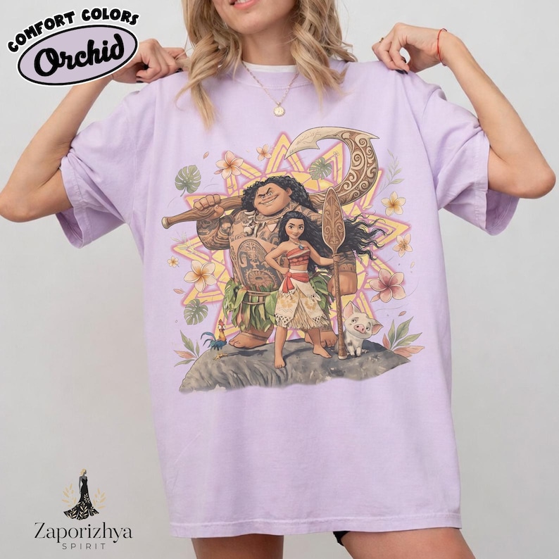 May include: A light purple t-shirt featuring a graphic of characters from a popular animated movie. The design includes a large figure holding a weapon, a young woman, and a small pig. The shirt has the text "Comfort Colors Orchid" at the top.