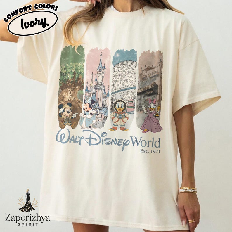 May include: Cream-coloured t-shirt with a graphic print of Walt Disney World characters and landmarks. The design includes Mickey Mouse, Minnie Mouse, Donald Duck, and Daisy Duck, with the text "Walt Disney World Est. 1971". The shirt has a loose fit.