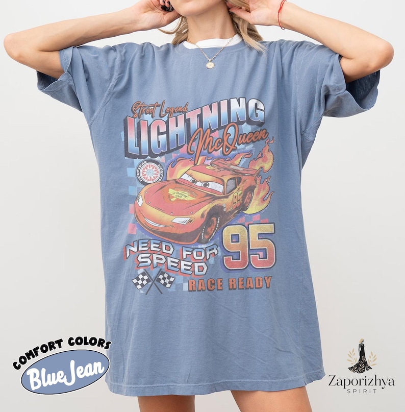 May include: Blue jean-colored t-shirt featuring Lightning McQueen from the movie Cars. The graphic includes the text "Street Legend Lightning McQueen", "Need for Speed", and "Race Ready". The number "95" is prominently displayed.