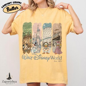 May include: Yellow t-shirt with a graphic featuring Mickey Mouse, Minnie Mouse, Donald Duck, and Daisy Duck, and the text "Walt Disney World Est. 1971." The shirt has the words "Comfort Colors Butter" printed on it.