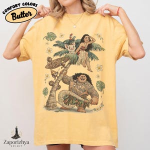 Może przedstawiać: Ż&oacute;łta koszulka z grafiką przedstawiającą postacie z popularnego filmu animowanego. Projekt zawiera palmę, postacie i napis "Comfort Colors Butter". Koszulka ma luźny kr&oacute;j.