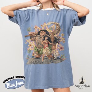 May include: Blue jean Comfort Colors t-shirt featuring a colorful graphic of characters from a popular animated movie. The design includes a large figure with tattoos, a young woman, a pig, and a rooster. The shirt has the words "Comfort Colors" and "Blue Jean" printed on it.