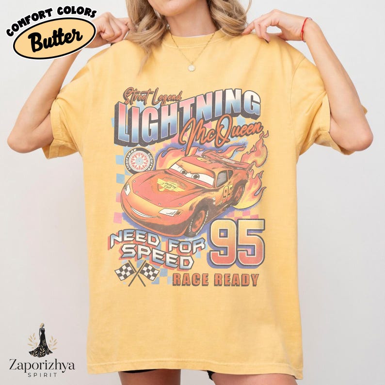 May include: Butter-colored t-shirt featuring a graphic of Lightning McQueen from the movie Cars. The design includes the text "Street Legend Lightning McQueen", "Need for Speed", and "Race Ready", with the number "95" prominently displayed.