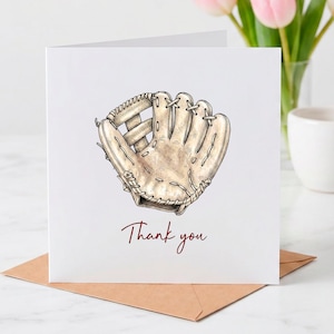 May include: A square white greeting card featuring a detailed illustration of a tan leather baseball glove in the center. Below the glove, the text Thank you is printed in a dark red script font. The card is folded and stands upright.