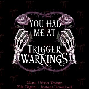 Può includere: Un grafico digitale su sfondo nero con due mani scheletriche che tengono rose viola. Il testo recita YOU HAD ME AT TRIGGER WARNINGS in caratteri bianchi. Il design è incorniciato da viti spinose e da un motivo di piccoli fiocchi rossi.