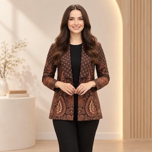 Könnte beinhalten: Ein langärmeliger Blazer mit einem batik-inspirierten Muster in Dunkelbraun und Hellbraun, ausgestattet mit einem breiten Revers, getragen über einem einfarbigen schwarzen Oberteil und einer schwarzen Hose. Die Jacke hat eine strukturierte Passform.