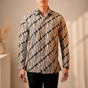 May include: A long-sleeved button-down shirt featuring a repeating dark brown and beige batik-style pattern. The shirt has a standard collar, a front button placket, and buttoned cuffs, worn over solid black trousers to complete the ensemble.