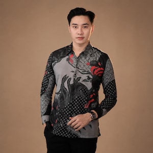 May include: A patterned long-sleeved shirt in grey, black, and red. The shirt has a button-down design with a distinctive floral and geometric pattern. The sleeves and collar have a contrasting design. The shirt is worn with black trousers.