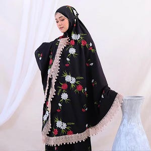 May include: Black prayer garment with floral embroidery in red, white, and green. The garment has a scalloped lace trim in a light beige colour. The head covering also features matching floral embroidery.